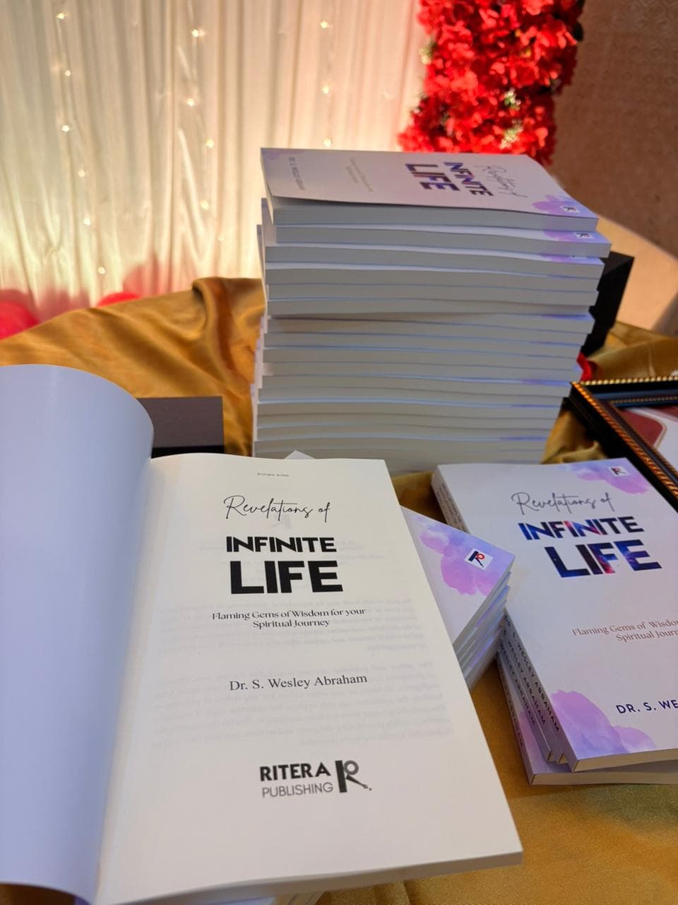 A tall stack of freshly printed copies of Revelations of Infinite Life at a Ritera book launch